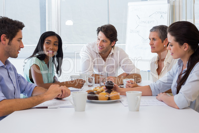 Workers working while enjoying hot drinks and muffins