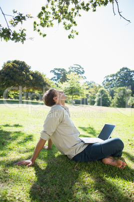 Stylish relaxed man using his laptop in the park
