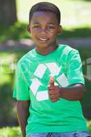 Young boy sitting on grass in recycling tshirt showing thumb up