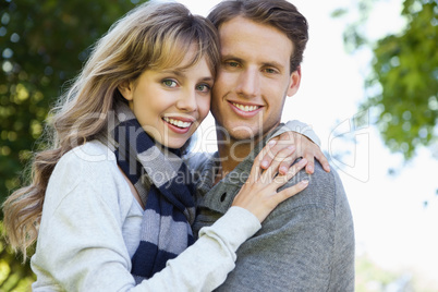 Cute couple embracing and smiling at camera in the park