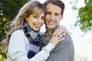 Cute couple embracing and smiling at camera in the park