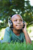 Little boy lying on grass listening to music