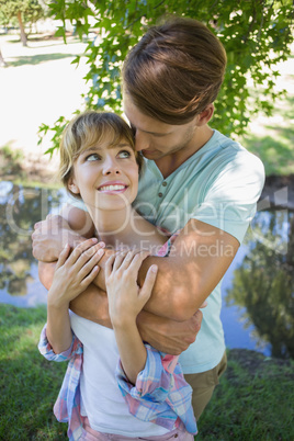 Affectionate young couple standing together in the park smiling