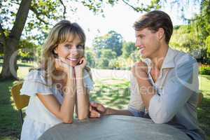 Cute couple sitting outside at a cafe with woman smiling at came