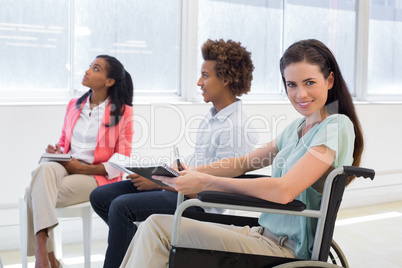 Attractive businesswoman in wheelchair smiling in the workplace