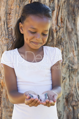 Little girl holding a butterfly in the park