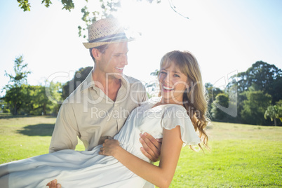 Cute blonde smiling while being lifted by boyfriend in the park