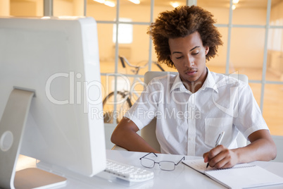 Casual young businessman writing at his desk