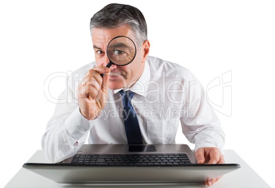 Mature businessman examining with magnifying glass