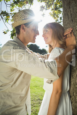 Cute couple leaning against tree in the park