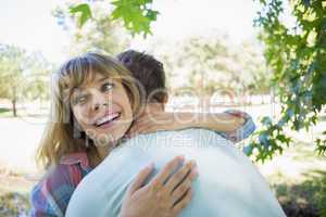 Pretty blonde smiling in a park while hugging boyfriend