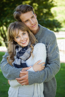 Cute couple hugging with girl smiling at camera in the park