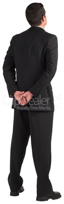 Businessman standing and looking with hands behind back