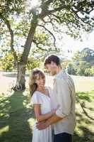 Smiling couple standing and embracing in park