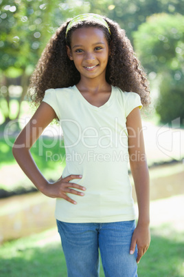 Young girl smiling at the camera in the park with hand on hip Young girl smiling at the camera in the park with hand on hip