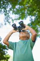 Little boy looking up through binoculars in the park