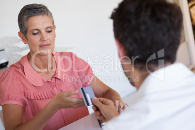 Casual saleswoman taking credit card from customer