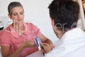 Casual saleswoman taking credit card from customer