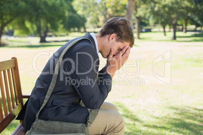 Worried businessman sitting on park bench