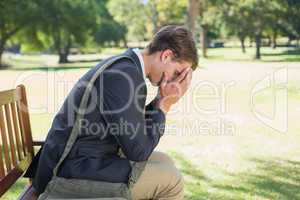 Worried businessman sitting on park bench