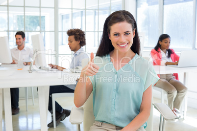 Attractive businesswoman giving thubms up to camera