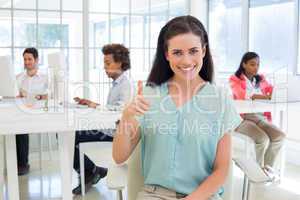 Attractive businesswoman giving thubms up to camera