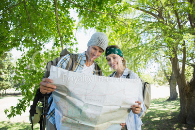 Active smiling couple on a hike consulting the map