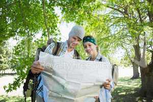 Active smiling couple on a hike consulting the map