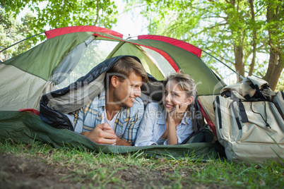 Cute couple lying in their tent smiling at each other