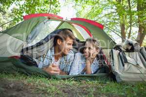 Cute couple lying in their tent smiling at each other