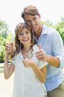 Attractive couple smiling at camera and showing thumbs up in the