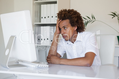 Casual stressed businessman looking at his computer