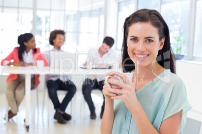 Attractive businesswoman drinking hot beverage with colleagues i