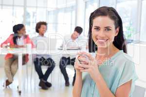 Attractive businesswoman drinking hot beverage with colleagues i
