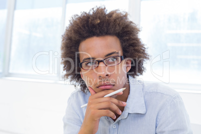 Attractive businessman thinking and holding a pencil