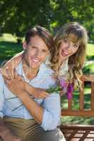 Cute couple smiling at camera in the park with girl holding flow