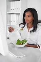 Happy pretty businesswoman eating a salad at her desk