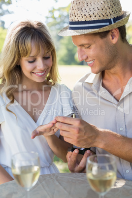 Man placing engagement ring on fiancees finger