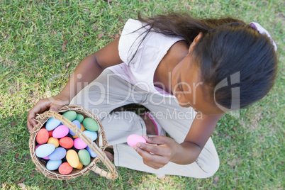 Little girl sitting on grass counting easter eggs