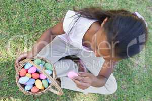 Little girl sitting on grass counting easter eggs