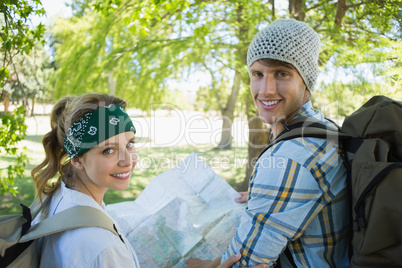 Active couple on a hike consulting the map smiling at camera