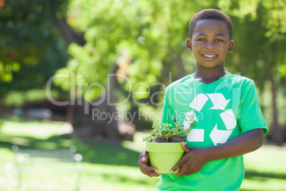 Young boy in recycling tshirt holding potted plant