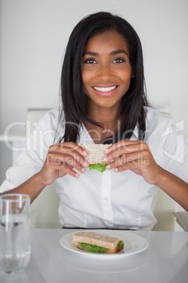 Pretty businesswoman eating a sandwich at her desk