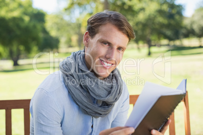 Stylish young man holding journal smiling at camera