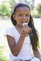 Little girl sitting on grass eating