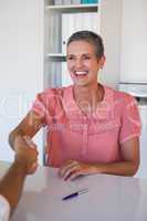 Laughing businesswoman shaking hands at desk