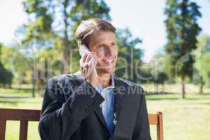 Casual businessman talking on phone on park bench