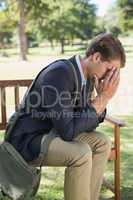 Worried businessman sitting on park bench