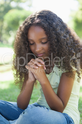 Young girl praying in the park