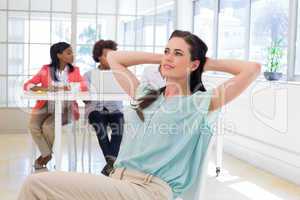 Attractive office worker relaxing with colleagues working behind